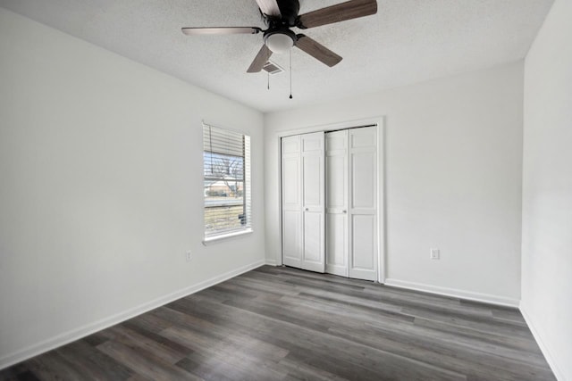 unfurnished bedroom featuring ceiling fan, dark wood-type flooring, a textured ceiling, and a closet