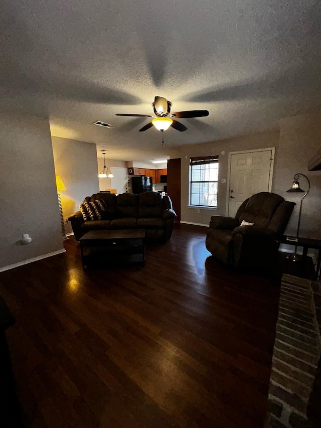 living room featuring ceiling fan, dark hardwood / wood-style floors, and a textured ceiling