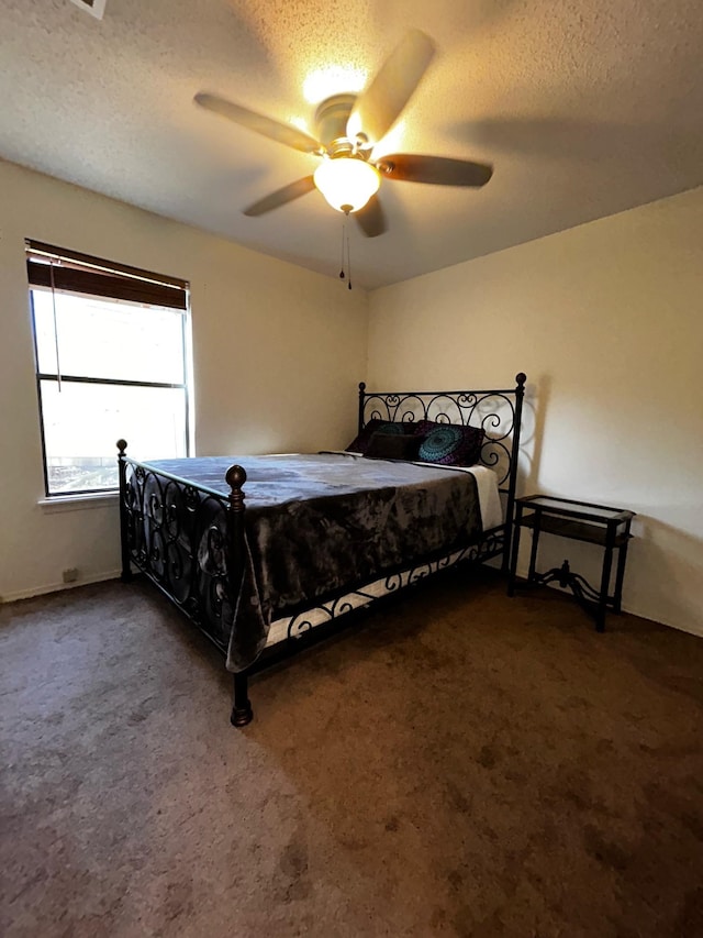 carpeted bedroom with ceiling fan and a textured ceiling