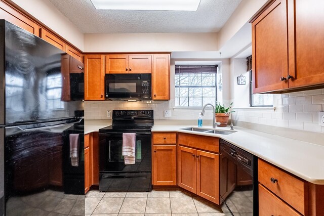 kitchen with tasteful backsplash, sink, light tile patterned floors, and black appliances