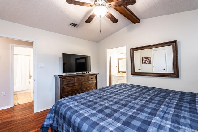 bedroom featuring ensuite bathroom, dark hardwood / wood-style floors, lofted ceiling with beams, ceiling fan, and a textured ceiling