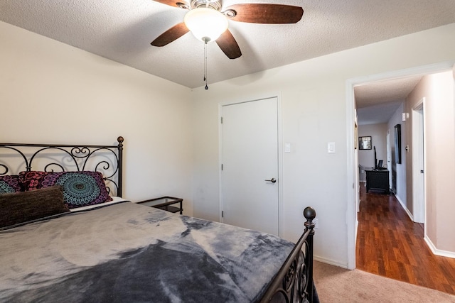 bedroom with ceiling fan, dark carpet, and a textured ceiling