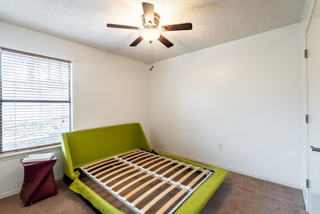 carpeted bedroom with ceiling fan, multiple windows, and a textured ceiling