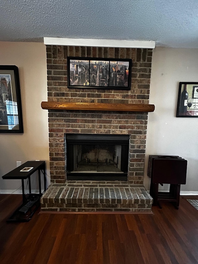 room details with hardwood / wood-style flooring, a brick fireplace, and a textured ceiling