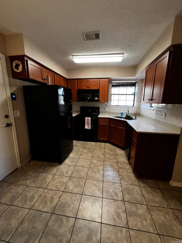 kitchen featuring tasteful backsplash, sink, light tile patterned floors, black appliances, and a textured ceiling