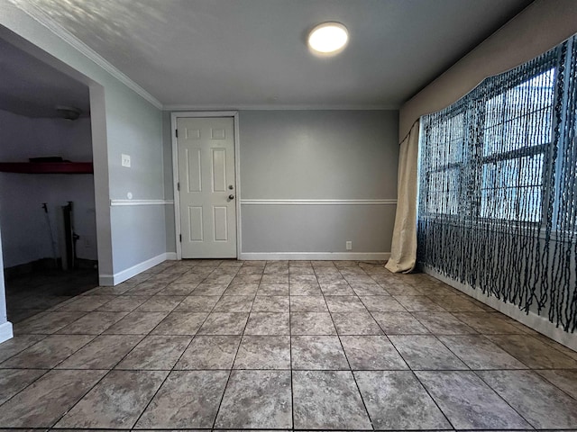 tiled empty room featuring crown molding