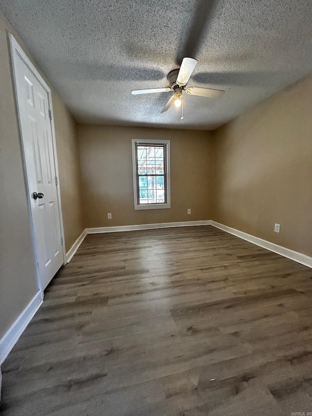 unfurnished room with a textured ceiling, dark wood-type flooring, and ceiling fan