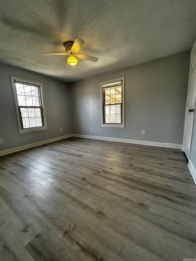 unfurnished room with ceiling fan, a textured ceiling, dark hardwood / wood-style floors, and a healthy amount of sunlight