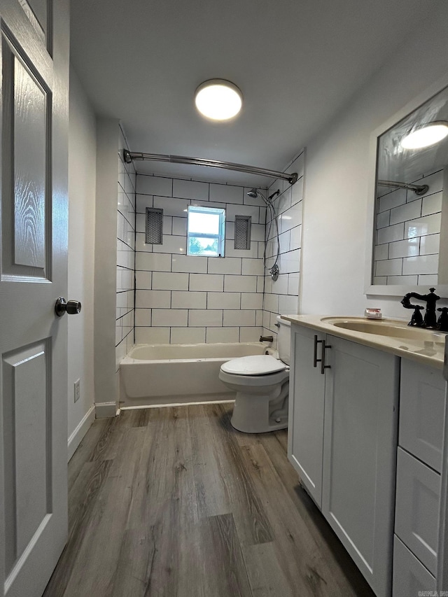 full bathroom featuring vanity, toilet, tiled shower / bath combo, and hardwood / wood-style floors