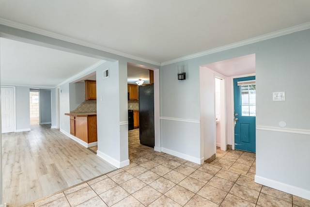 interior space featuring black refrigerator, crown molding, light tile patterned flooring, and tasteful backsplash