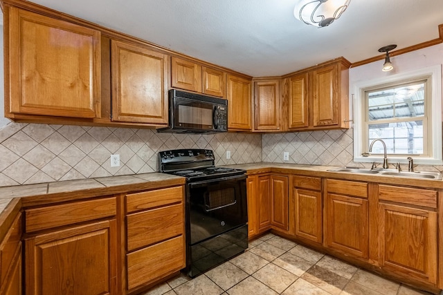 kitchen with sink, light tile patterned floors, tile counters, black appliances, and decorative backsplash