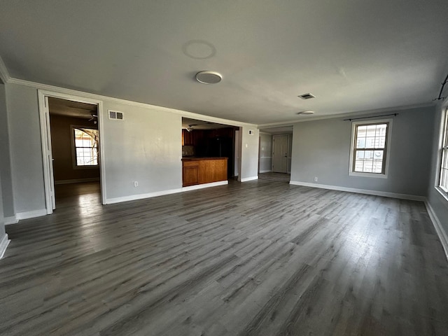 unfurnished living room with dark hardwood / wood-style flooring, crown molding, and plenty of natural light