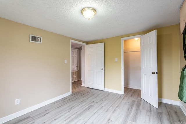 unfurnished bedroom with a closet, light hardwood / wood-style flooring, and a textured ceiling