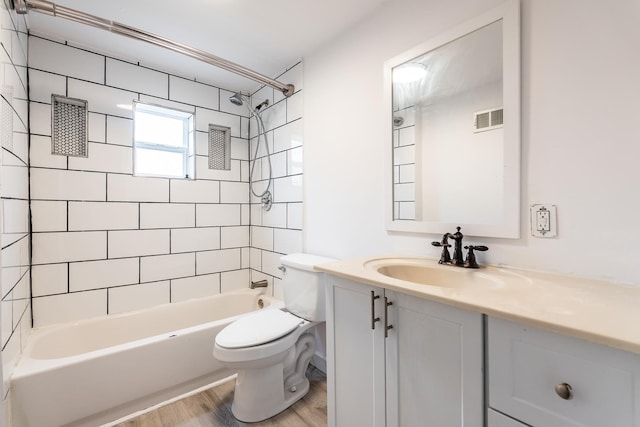 full bathroom with vanity, hardwood / wood-style floors, tiled shower / bath combo, and toilet