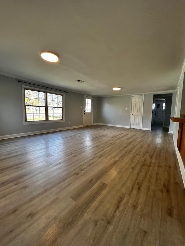 unfurnished living room featuring hardwood / wood-style floors and crown molding