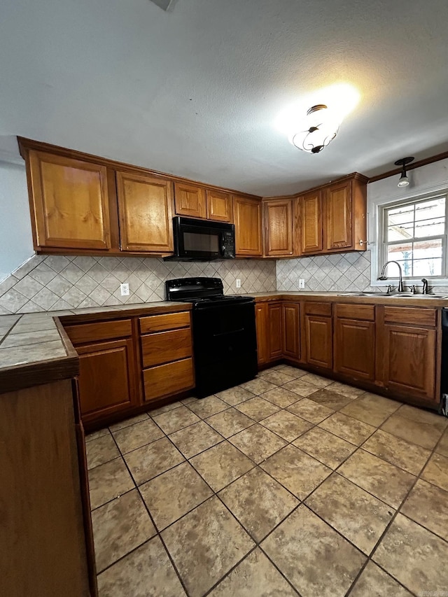 kitchen with light tile patterned flooring, sink, tasteful backsplash, tile countertops, and black appliances