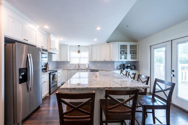 kitchen featuring white cabinetry, hanging light fixtures, a kitchen bar, and appliances with stainless steel finishes