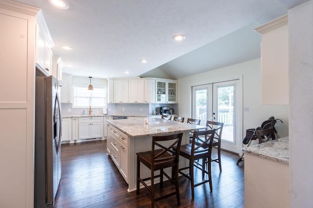 kitchen featuring pendant lighting, stainless steel fridge, a center island, and white cabinets