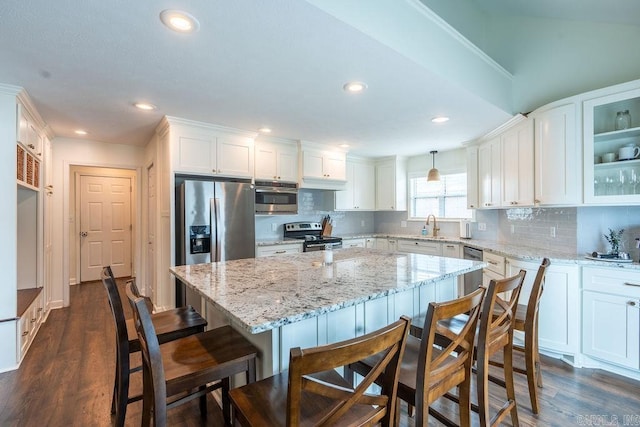 kitchen featuring sink, white cabinetry, stainless steel appliances, a kitchen island, and decorative backsplash