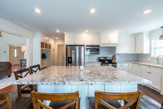 kitchen with a breakfast bar area, tasteful backsplash, appliances with stainless steel finishes, a kitchen island, and white cabinets