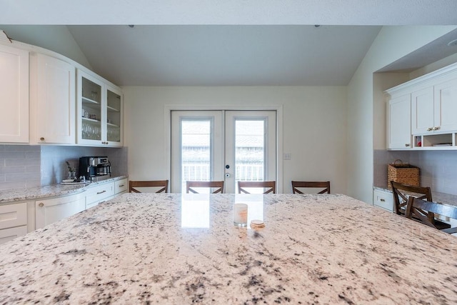 kitchen featuring tasteful backsplash, light stone counters, a breakfast bar area, and white cabinets