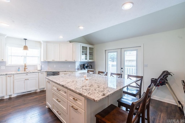 kitchen with pendant lighting, sink, a kitchen bar, a kitchen island, and decorative backsplash