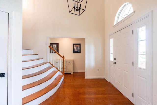 foyer entrance featuring a towering ceiling, dark hardwood / wood-style floors, and a wealth of natural light