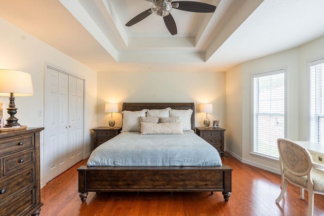 bedroom with a tray ceiling, a closet, ceiling fan, and hardwood / wood-style flooring