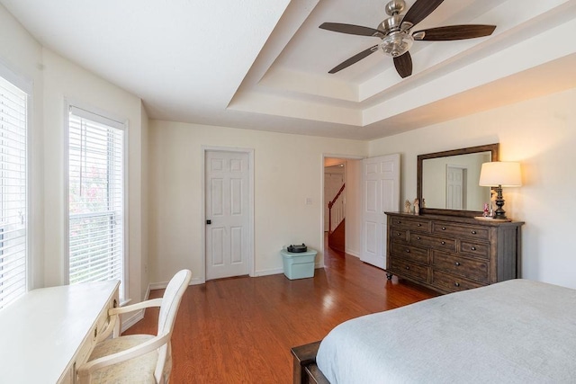 bedroom with dark hardwood / wood-style floors, a raised ceiling, and ceiling fan