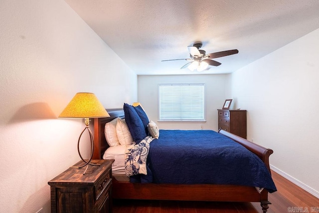 bedroom with a textured ceiling, dark wood-type flooring, and ceiling fan