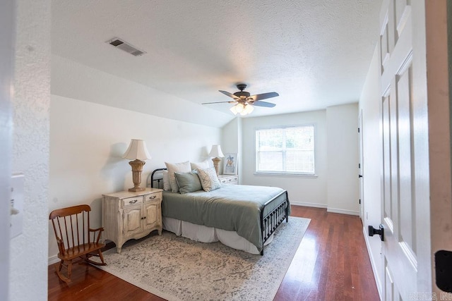 bedroom with ceiling fan, dark wood-type flooring, and a textured ceiling