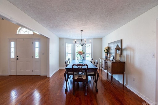 dining space with dark wood-type flooring, a notable chandelier, and a textured ceiling