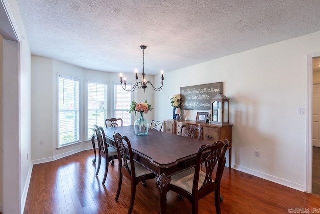 dining room featuring a textured ceiling, dark wood-type flooring, and a chandelier