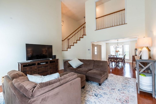 living room with hardwood / wood-style flooring, a towering ceiling, and a notable chandelier