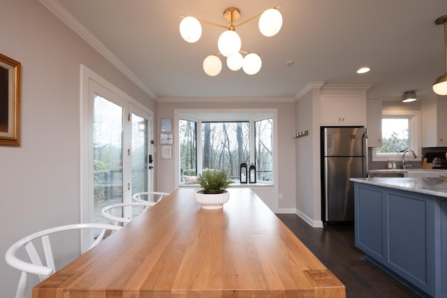 dining area featuring crown molding, dark hardwood / wood-style flooring, a chandelier, and sink