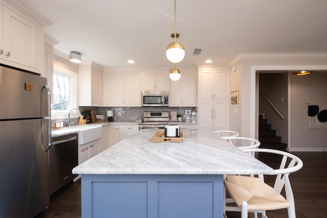 kitchen featuring pendant lighting, sink, a breakfast bar, appliances with stainless steel finishes, and a kitchen island