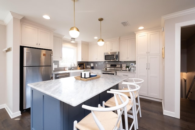 kitchen with stainless steel appliances, decorative light fixtures, a center island, and white cabinets