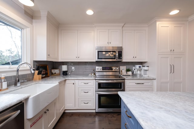 kitchen featuring light stone counters, appliances with stainless steel finishes, sink, and white cabinets