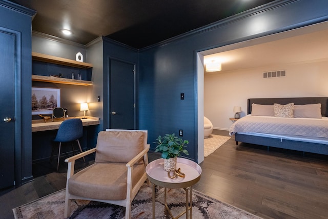 bedroom featuring built in desk, ornamental molding, and dark hardwood / wood-style floors