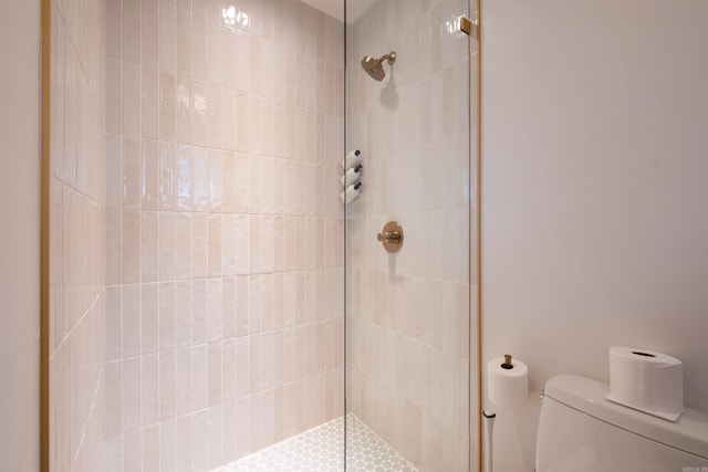 bathroom featuring tiled shower and toilet