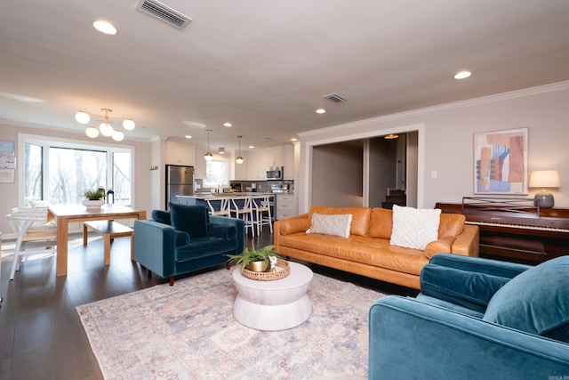 living room with crown molding, dark hardwood / wood-style floors, and an inviting chandelier