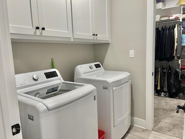 washroom with baseboards, light wood-style floors, cabinet space, and washer and dryer