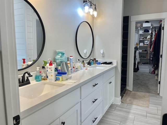 full bath featuring double vanity, a spacious closet, and a sink