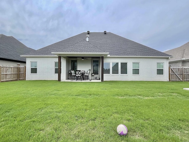 rear view of house featuring a patio area, a fenced backyard, a shingled roof, and a lawn