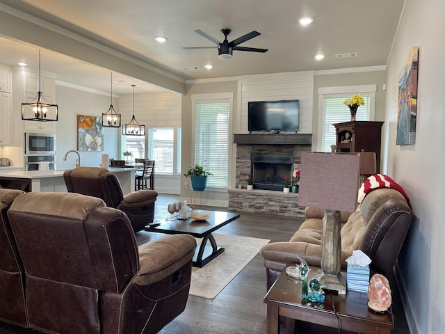 living area with visible vents, dark wood-type flooring, crown molding, a fireplace, and recessed lighting