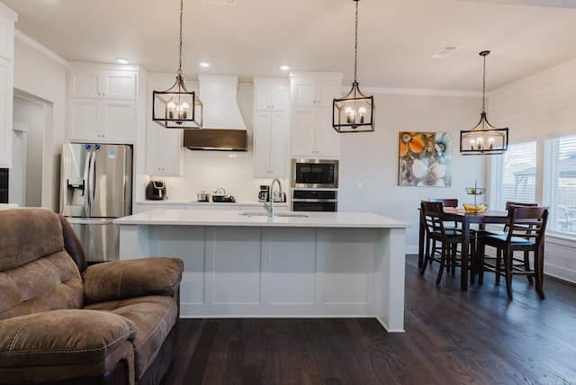 kitchen featuring a sink, light countertops, appliances with stainless steel finishes, hanging light fixtures, and custom range hood