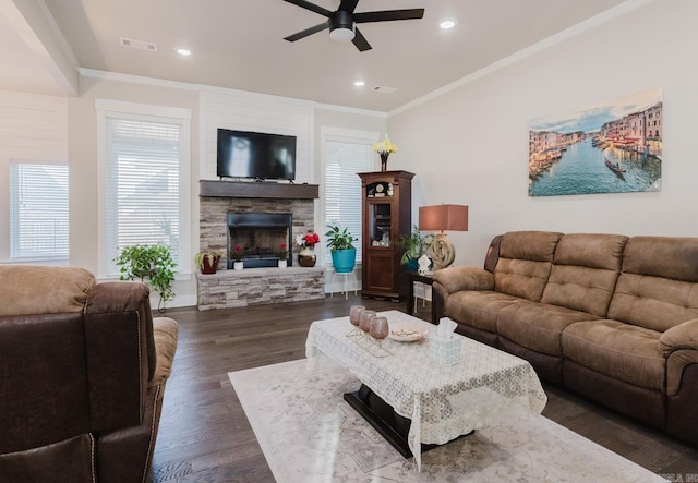 living area with visible vents, ceiling fan, dark wood-type flooring, crown molding, and a fireplace