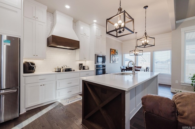 kitchen with pendant lighting, stainless steel appliances, light countertops, a sink, and premium range hood