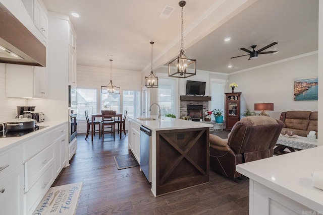 kitchen featuring light countertops, hanging light fixtures, appliances with stainless steel finishes, open floor plan, and a kitchen island with sink