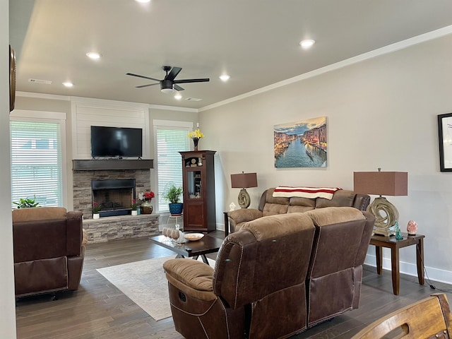 living area featuring dark wood-style floors, baseboards, ornamental molding, and a stone fireplace